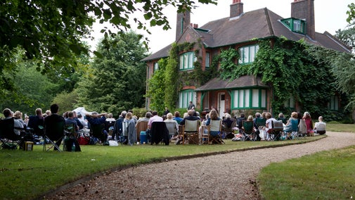 Audience at an outdoor theatre event with the house in the background at Shaw's Corner, Hertfordshire.